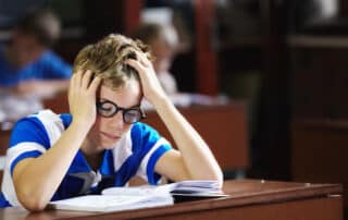 A student stressed in a classroom showing one of the signs they need a flexible online school schedule.