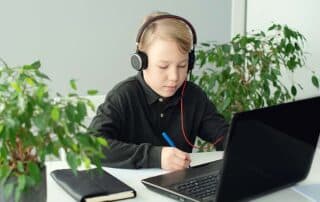 A young boy at home on a computer doing homeschool work.