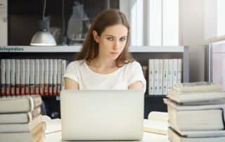 A parent on a computer at home struggling with choosing a live online high school for their child.
